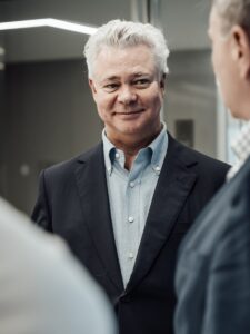 Anthony Brown smiling, whilst in conversation with two other people.